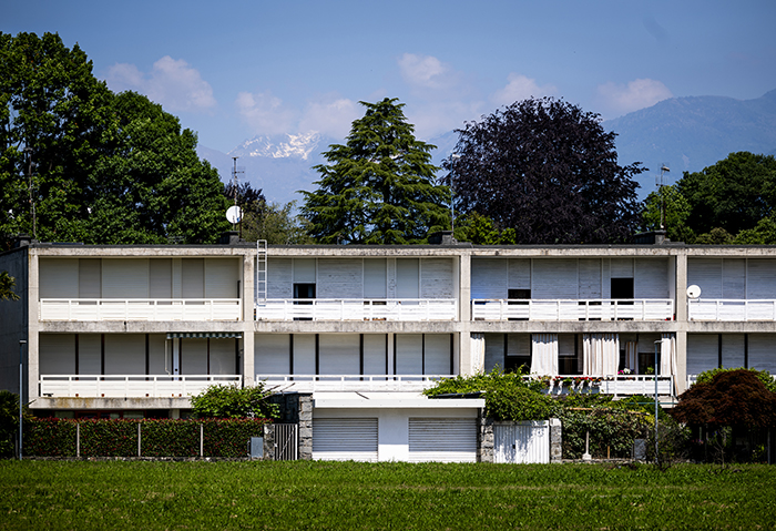 Palazzina residenziale modernista con balconi e persiane bianche su prato, cornice delle Alpi innevate vicino a Ivrea