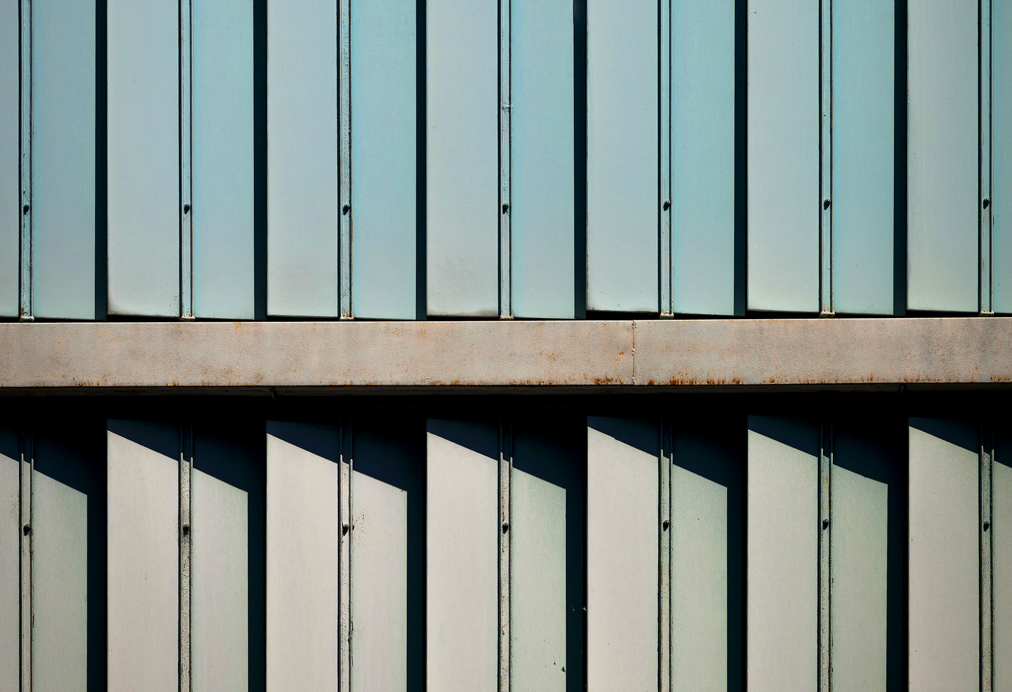 Facciata modulare metallica con listelli verticali e ombre geometriche, dettaglio di architettura industriale a Ivrea