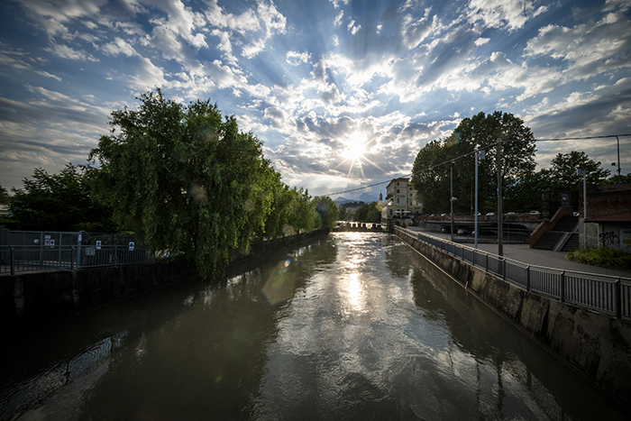Dora Baltea a Ivrea al tramonto, sole che si riflette sull'acqua tra gli argini urbani