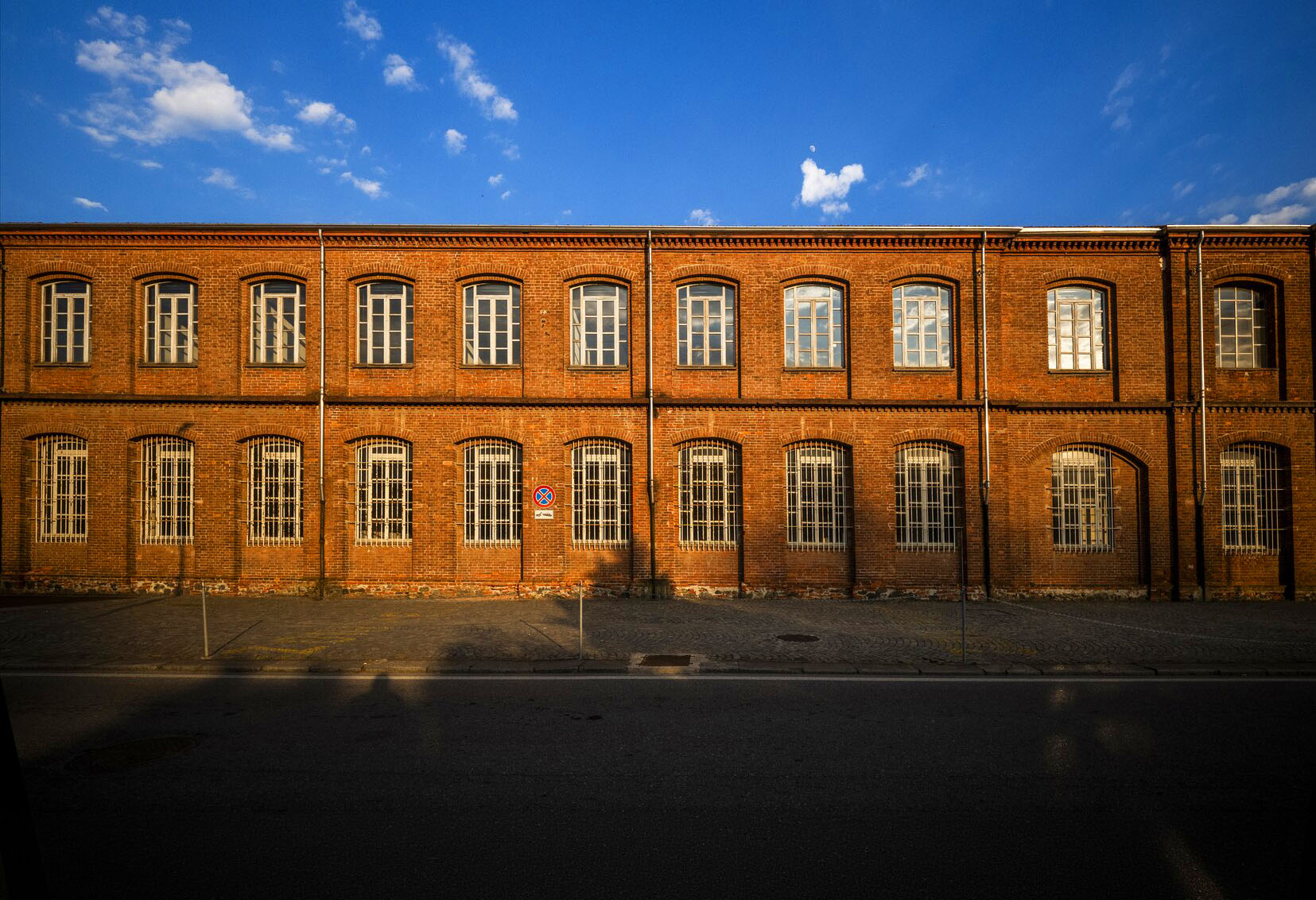 Ex stabilimento industriale Olivetti a Ivrea, facciata in mattoni rossi con due file di finestre ad arco al tramonto