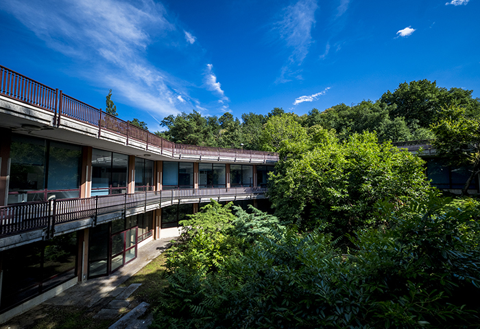Edificio modernista su due livelli con passerella esterna e cortile verde, esempio dell'architettura di Ivrea