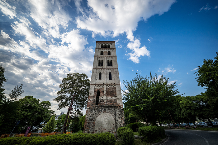 Torre campanaria medievale in pietra nel centro storico di Ivrea contro un cielo azzurro e nuvoloso